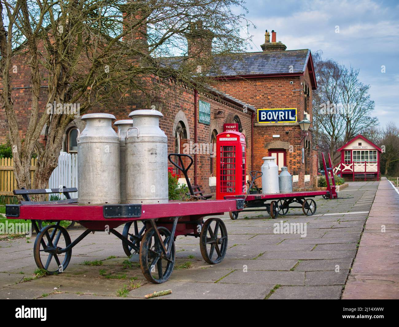 Il vecchio latte si inciterà su un carrello alla stazione ferroviaria di Hadlow Road a Wirral, Inghilterra, Regno Unito. Un museo del patrimonio storico di grado 2 Foto Stock