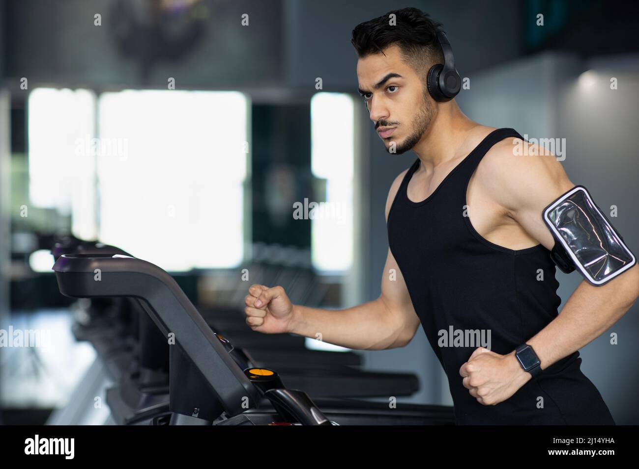 Ritratto di fiducioso Muscular Arab Man Training sul tapis roulant alla moderna palestra Foto Stock