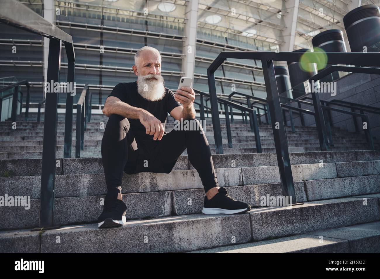 Vista completa del corpo dell'attraente uomo virile in pensione grigio  seduto su scale di pietra utilizzando il dispositivo gadget che chiacchiera  all'aperto Foto stock - Alamy