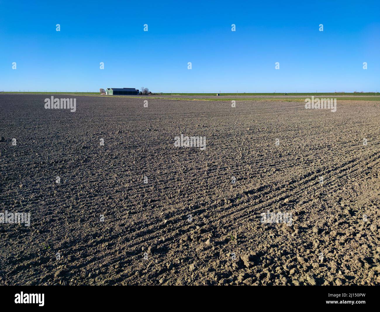 Cielo blu sopra i campi con fattoria in lontananza Foto Stock