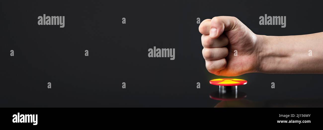La mano preme il grande pulsante rosso. Il concetto della minaccia della guerra nucleare. Una minaccia per il mondo con una valigia nucleare e una bomba. La mano Foto Stock
