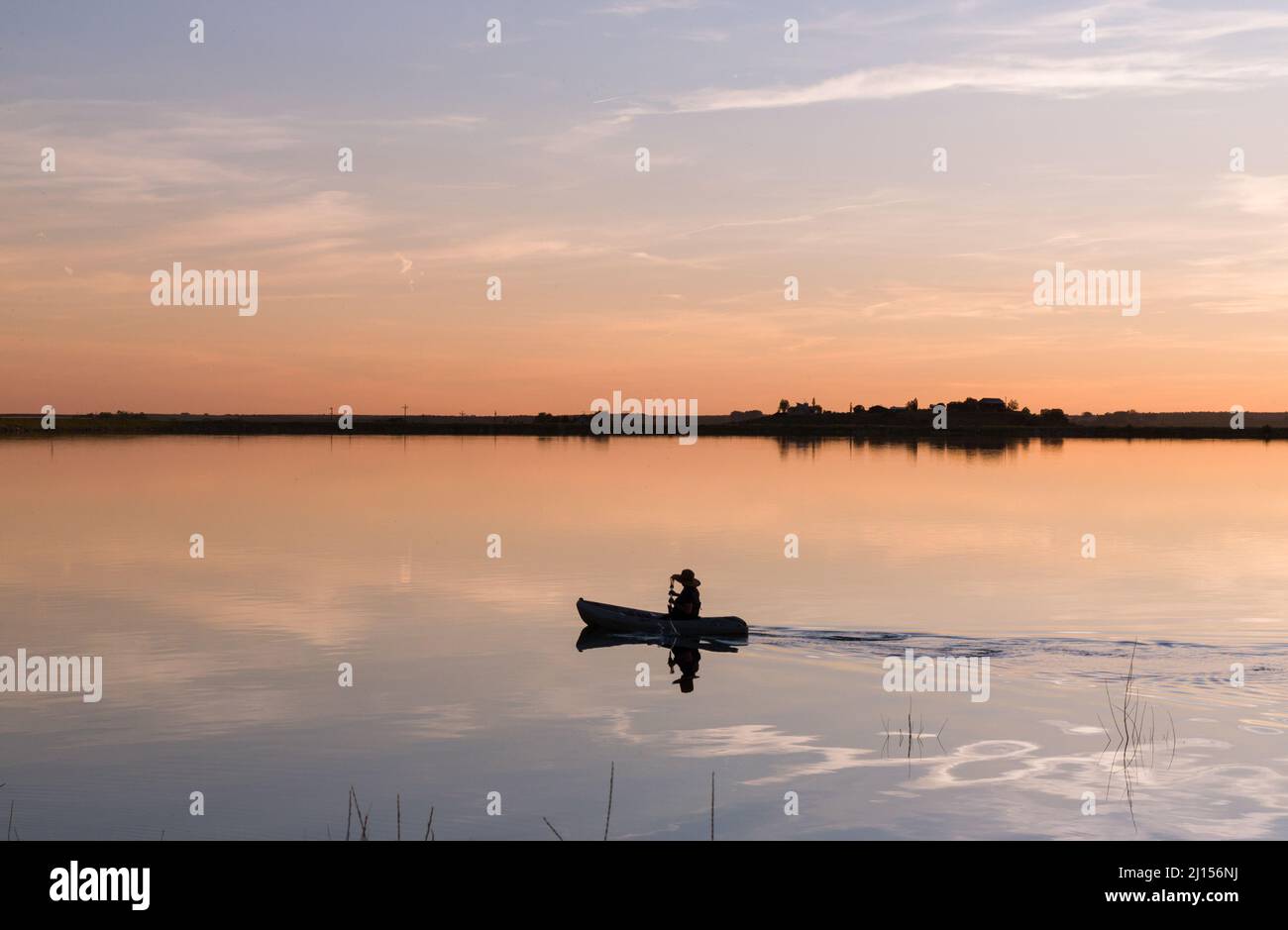 Canoa attraverso il lago al tramonto Foto Stock