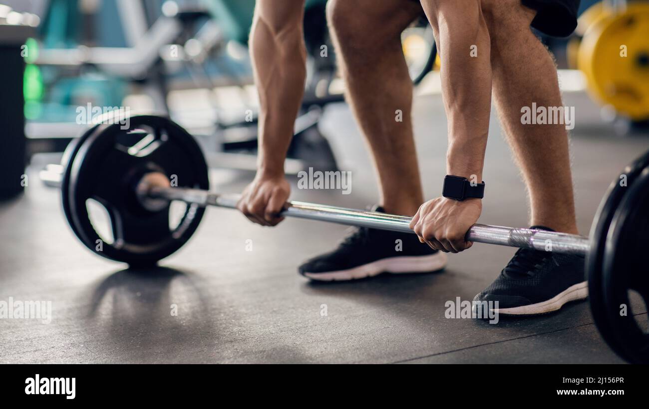 Ritratto di atleta maschile irriconoscibile che lavora con Barbell in palestra Foto Stock