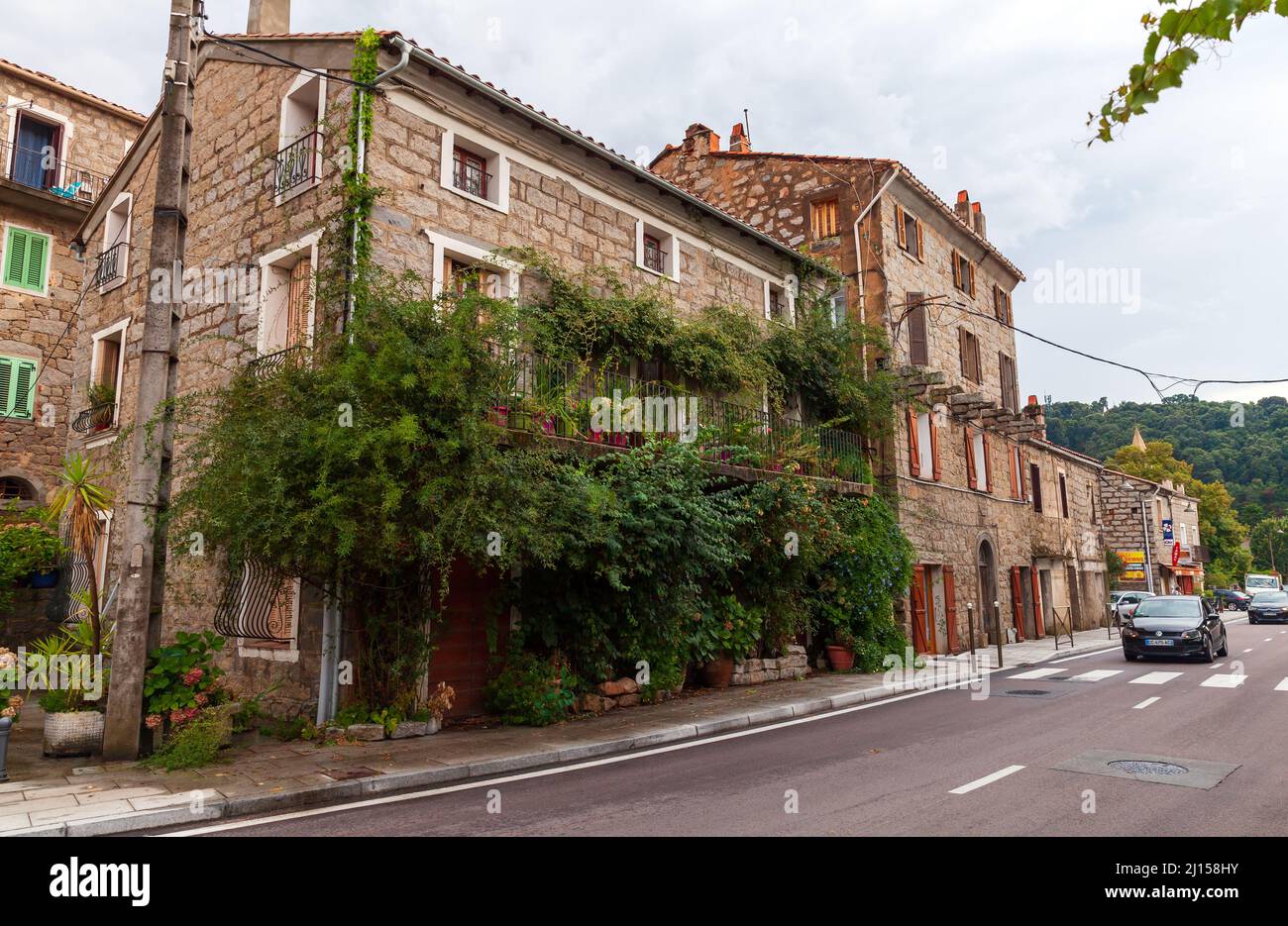 Petreto-Bicchisano, Francia - 18 agosto 2018: Vista sulla strada del centro storico con case e alberi in pietra, isola di Corsica Foto Stock