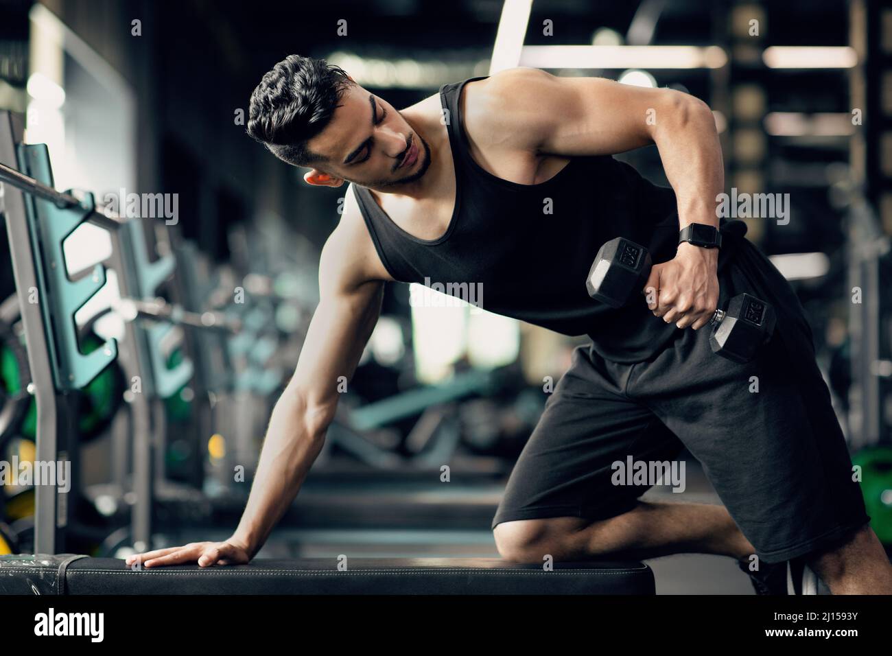 Giovane Muscle Middle Eastern Man allenarsi con Dumbbell alla moderna palestra Foto Stock