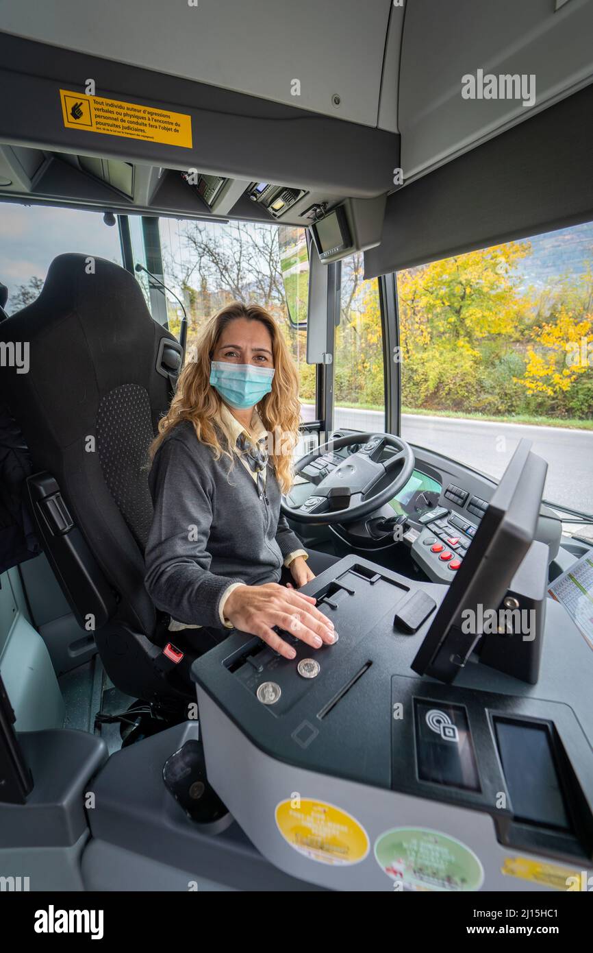 Scatto verticale di un conducente sorridente con una maschera che stampa un biglietto Foto Stock