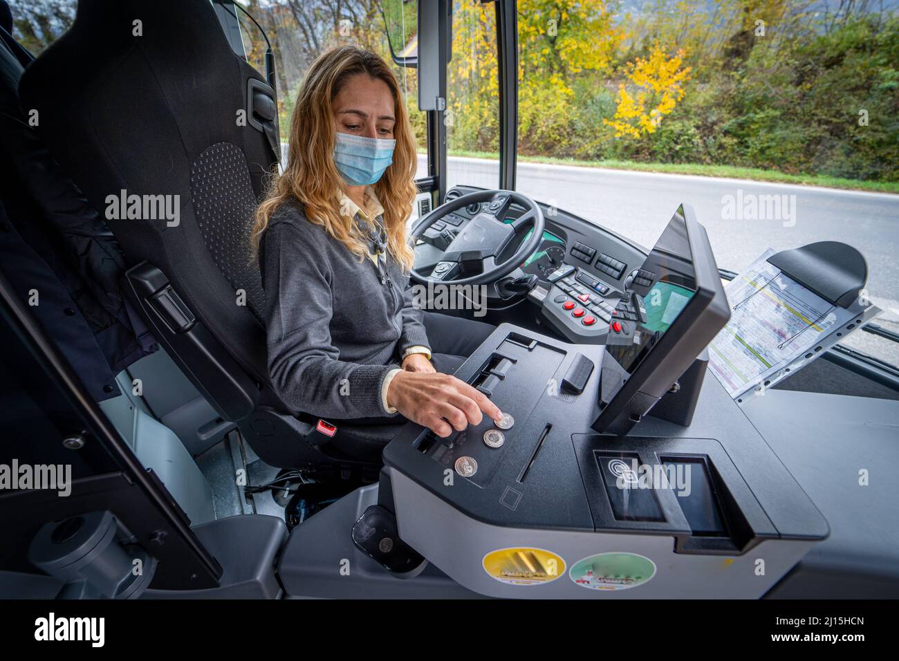 Giovane driver bus femminile in una maschera di conteggio cambiamento Foto Stock