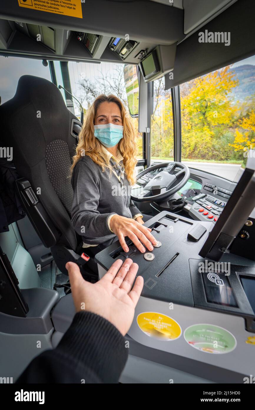 Scatto verticale di un driver bus femmina in una maschera che dà il cambiamento Foto Stock