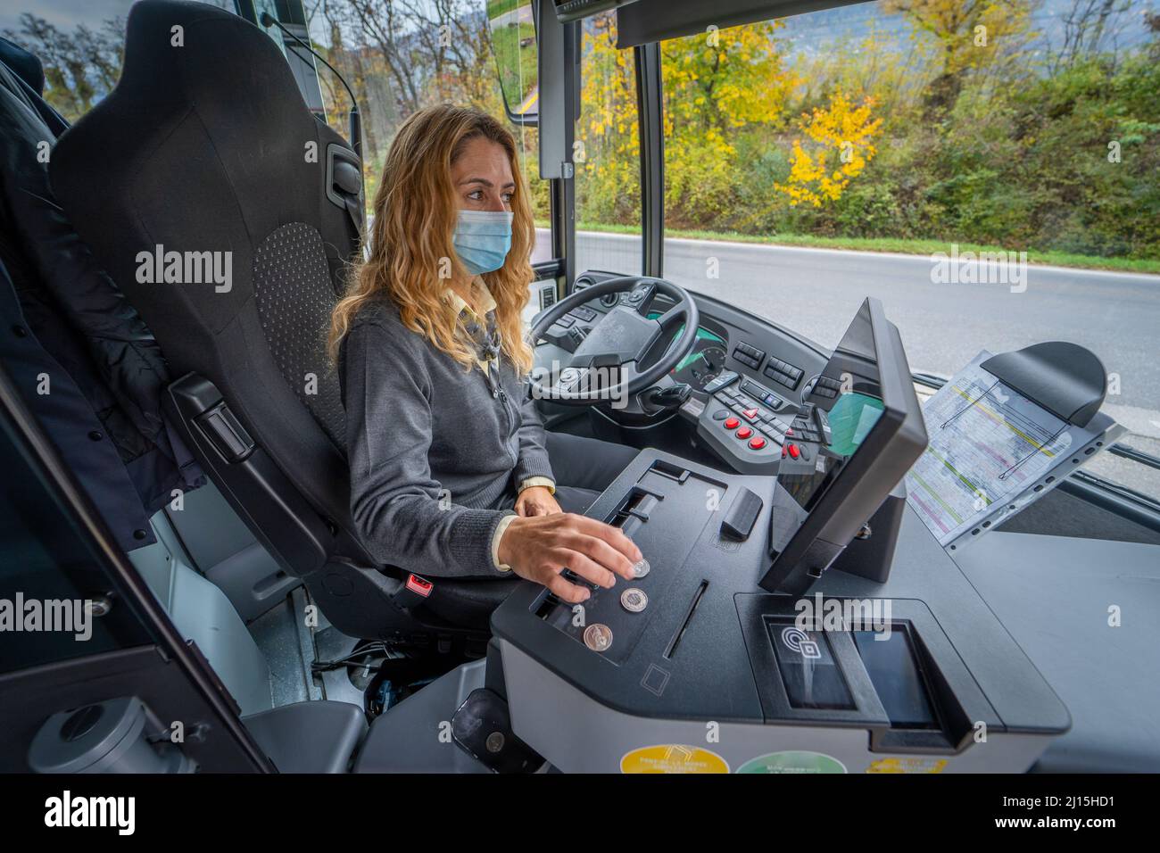 Giovane driver bus femminile in una maschera di conteggio cambiamento Foto Stock