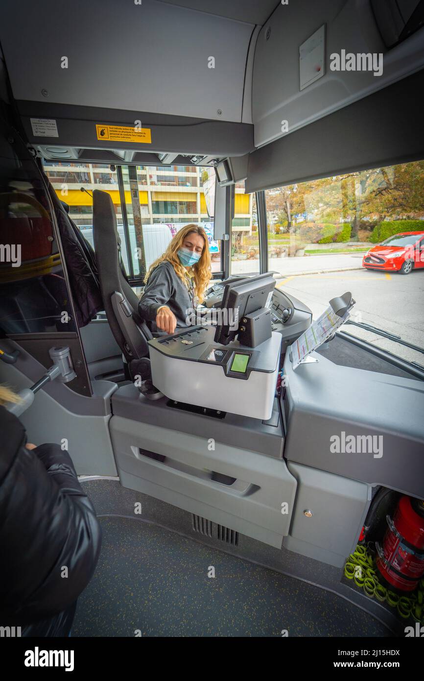 Scatto verticale di un conducente di bus femminile con una maschera che stampa un biglietto Foto Stock