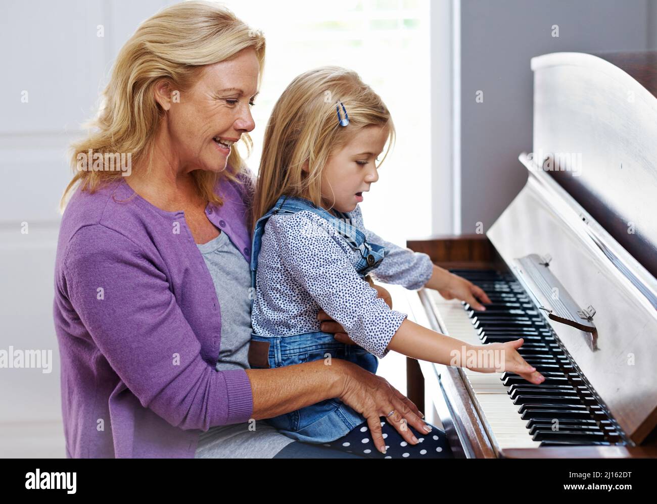 Mi ricorda sua madre. Carina bambina che viene insegnata come suonare il pianoforte da sua nonna. Foto Stock