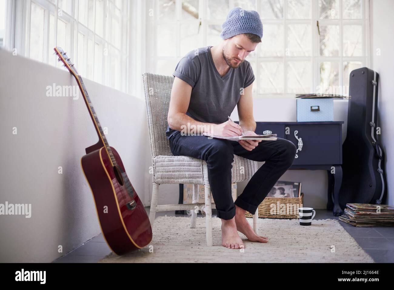 Affinare le sue abilità songwriting. Girato di un bel giovane uomo che scrive la sua canzone a casa. Foto Stock