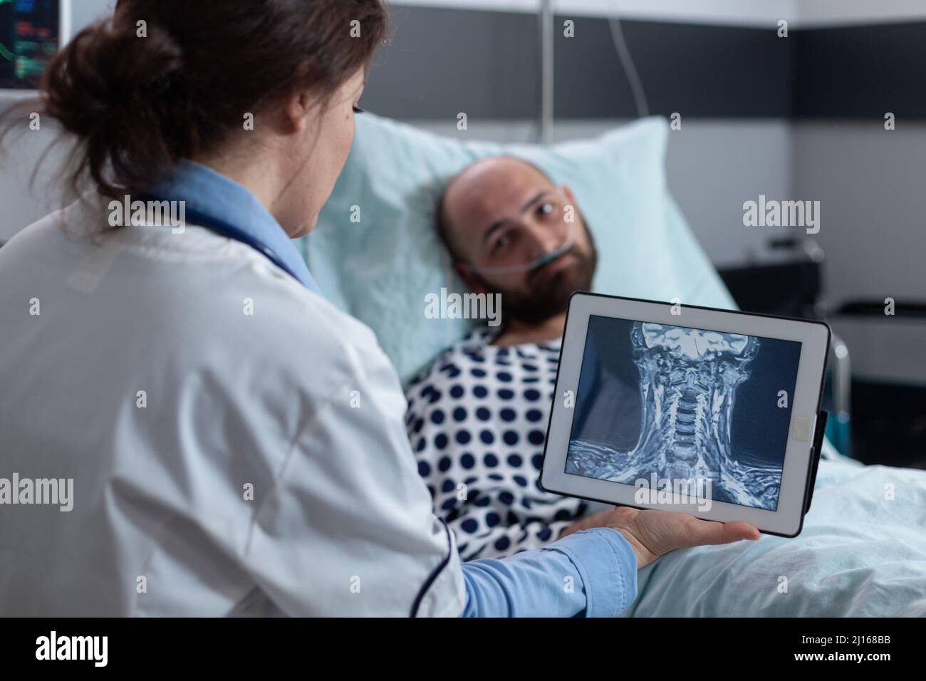 Medico che presenta al paziente opzioni per il trattamento di mal di gola mentre guarda la scansione mri su tablet digitale. Uomo di mezza età con problemi cervicali con bassa saturazione di ossigeno. Foto Stock