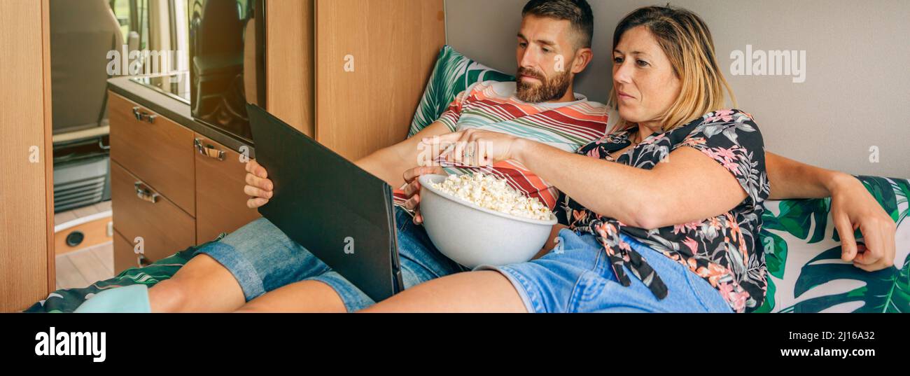 Coppia che guarda un film puntando tablet sdraiato sul letto del loro camper furgone Foto Stock