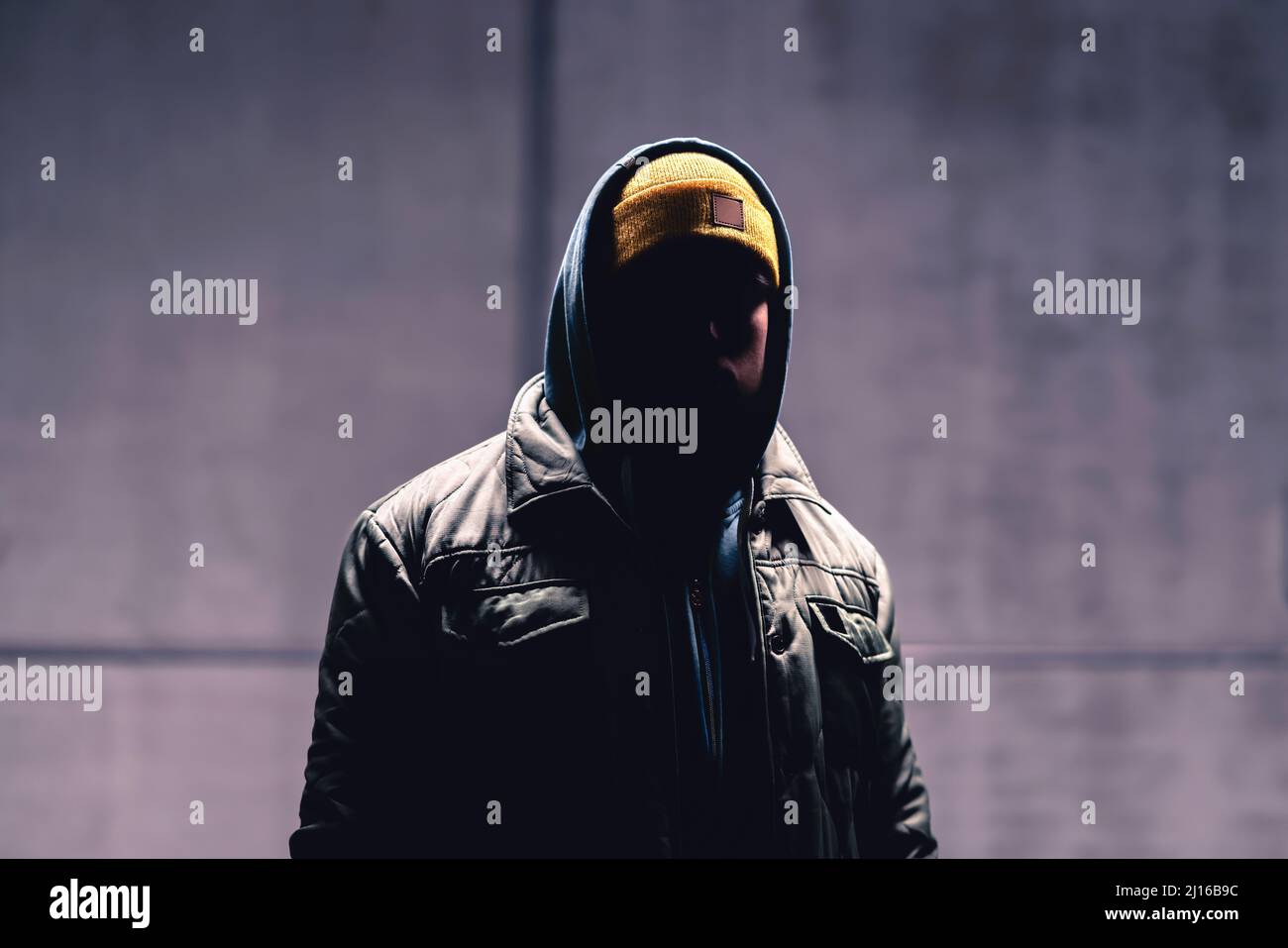 Hooded criminale nel buio. Mistero uomo con cappuccio. Gangster in strada urbana. Hooligan in felpa con cappuccio. Stalker con volto nascosto. Ladro sospetto sconosciuto. Foto Stock