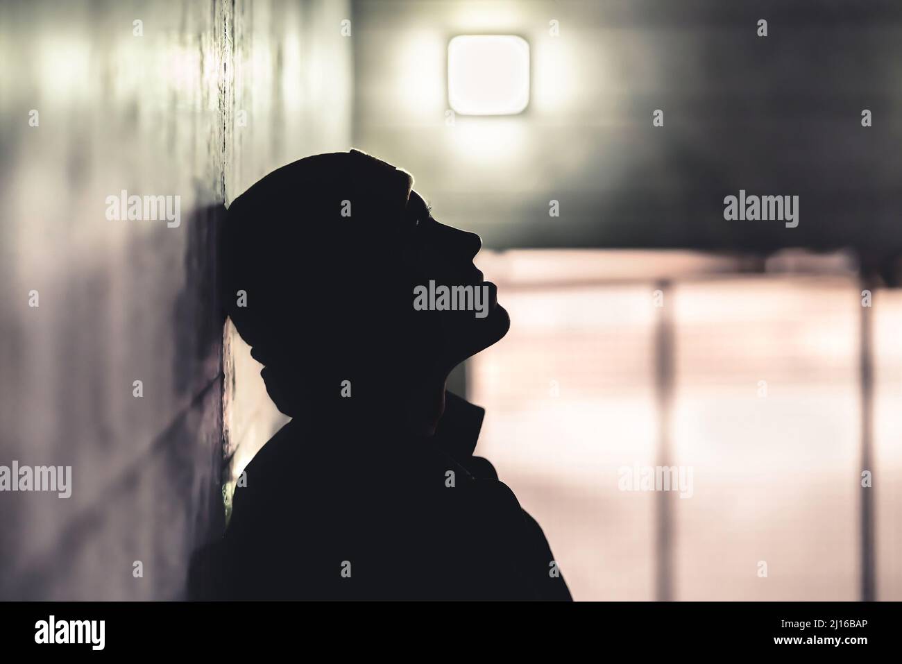 Grave uomo triste al buio. La persona depressa ansiosa soffre di trauma, solitudine o tossicodipendenza. I senzatetto sono fuori di vergogna dopo errore. Foto Stock