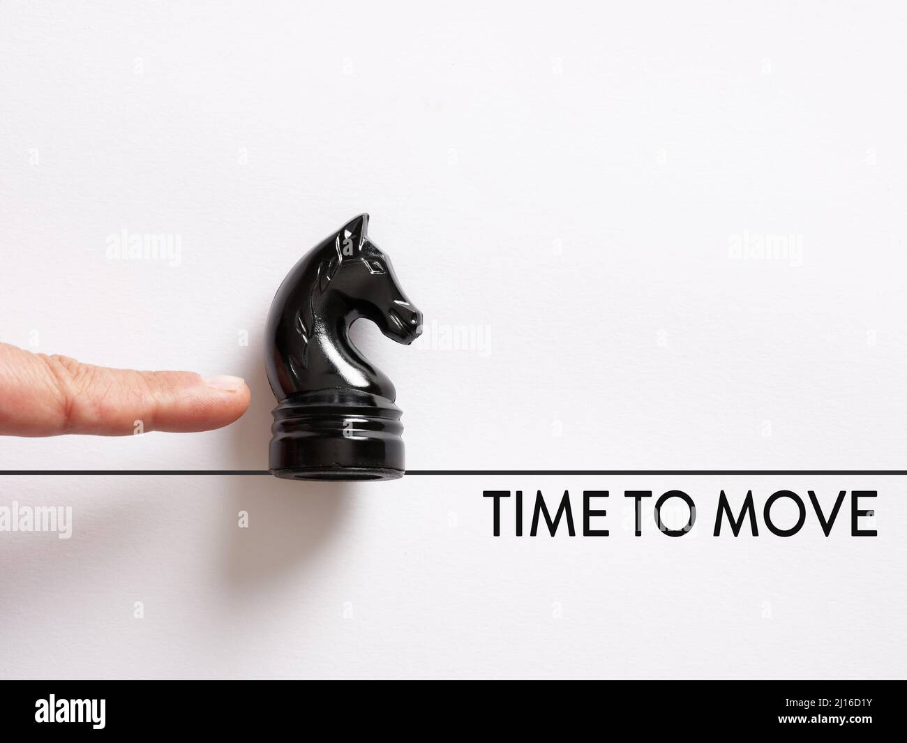 Dito che spinge il cavaliere degli scacchi con il messaggio tempo di muoversi. Agire o andare avanti nel business o nel concetto di vita personale. Foto Stock