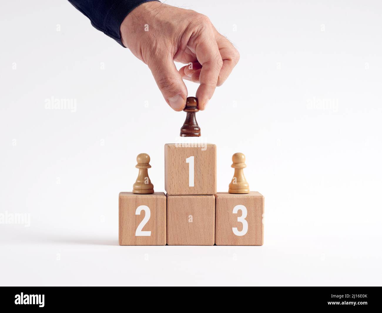 Mano posiziona la pedina del vincitore di diversi colori sul podio. Concetto di vincita, valutazione dei dipendenti, migliori prestazioni e successo. Foto Stock
