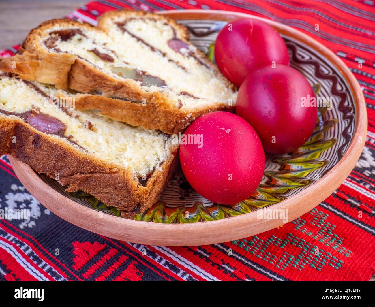 fette di pane dolce pasquale tradizionale o cozonac e uova decorate traditional, piatto pasquale rumeno, su stoffa da tavola Foto Stock