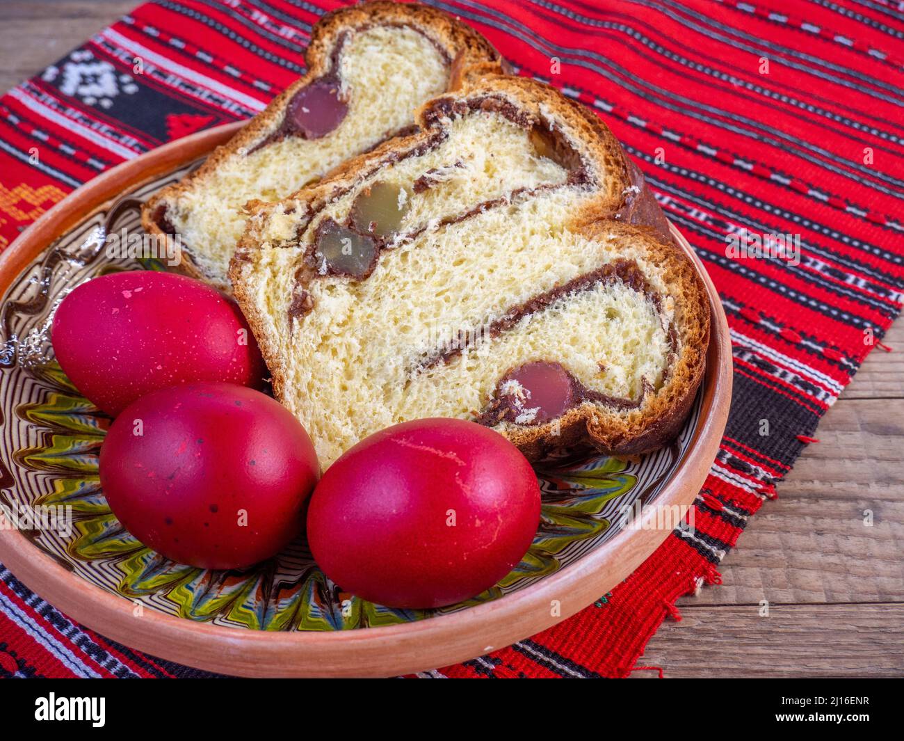fette di pane dolce pasquale tradizionale o cozonac e uova decorate traditional, piatto pasquale rumeno, su stoffa da tavola Foto Stock