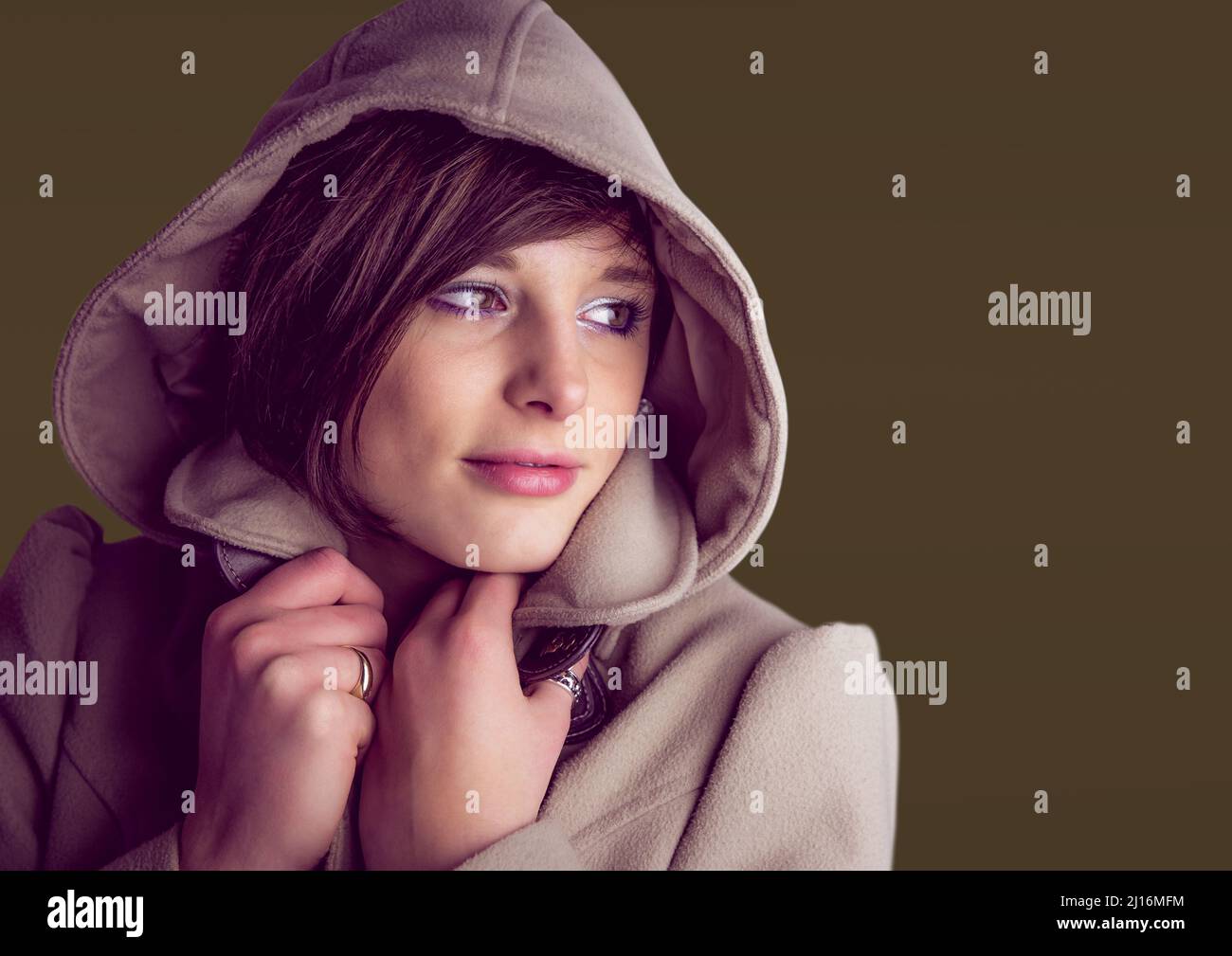 Donna caucasica che indossa una felpa con cappuccio contro lo spazio copia su sfondo marrone Foto Stock