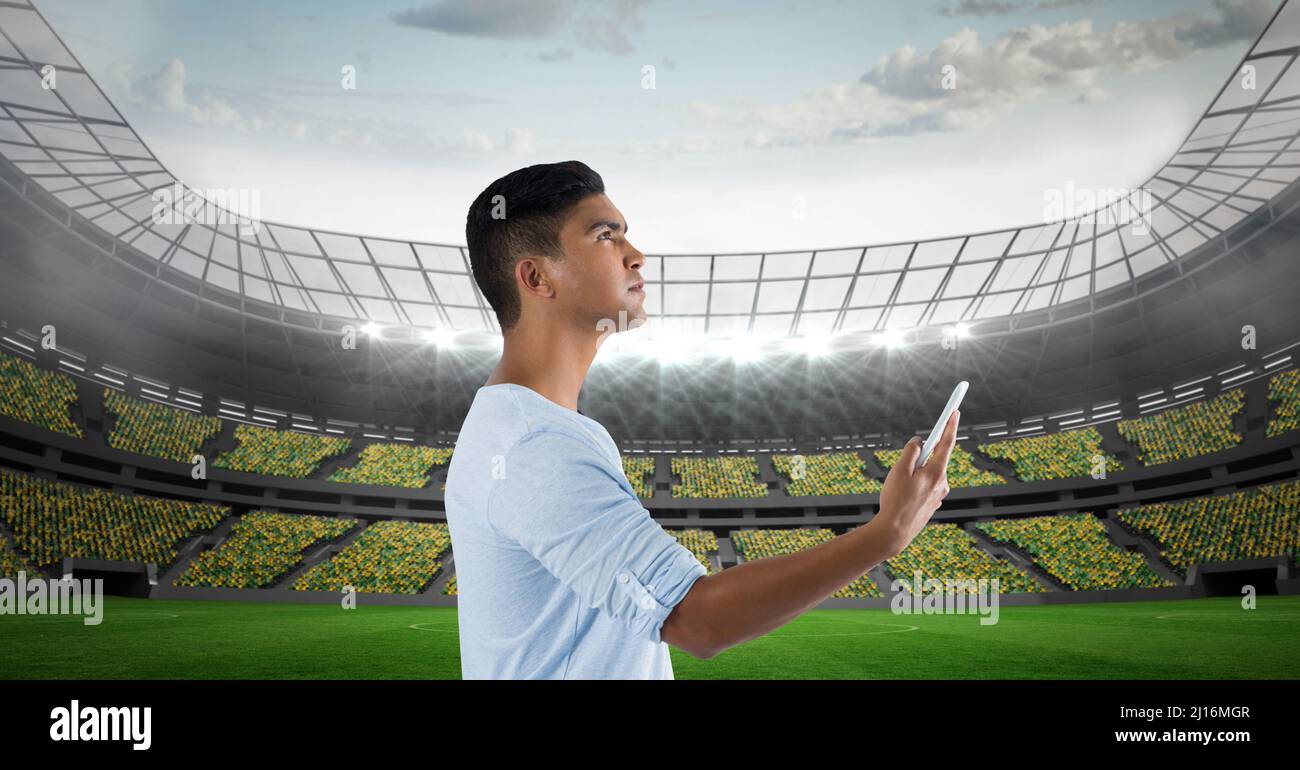 Immagine composita dell'uomo indiano che utilizza lo smartphone contro lo stadio sportivo Foto Stock