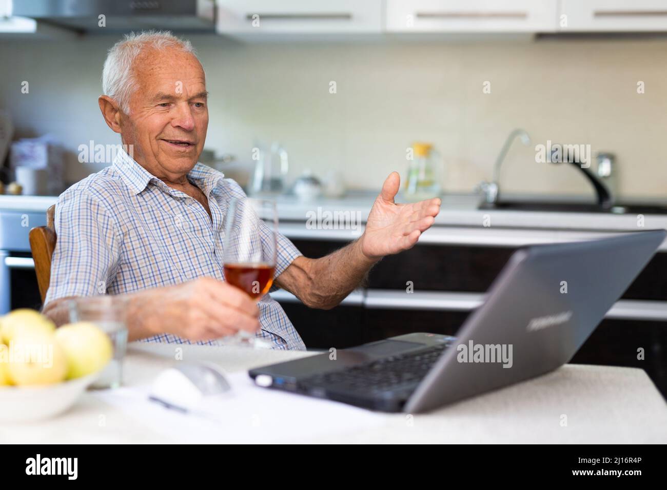 Uomo anziano con bicchiere di brandy e laptop Foto Stock