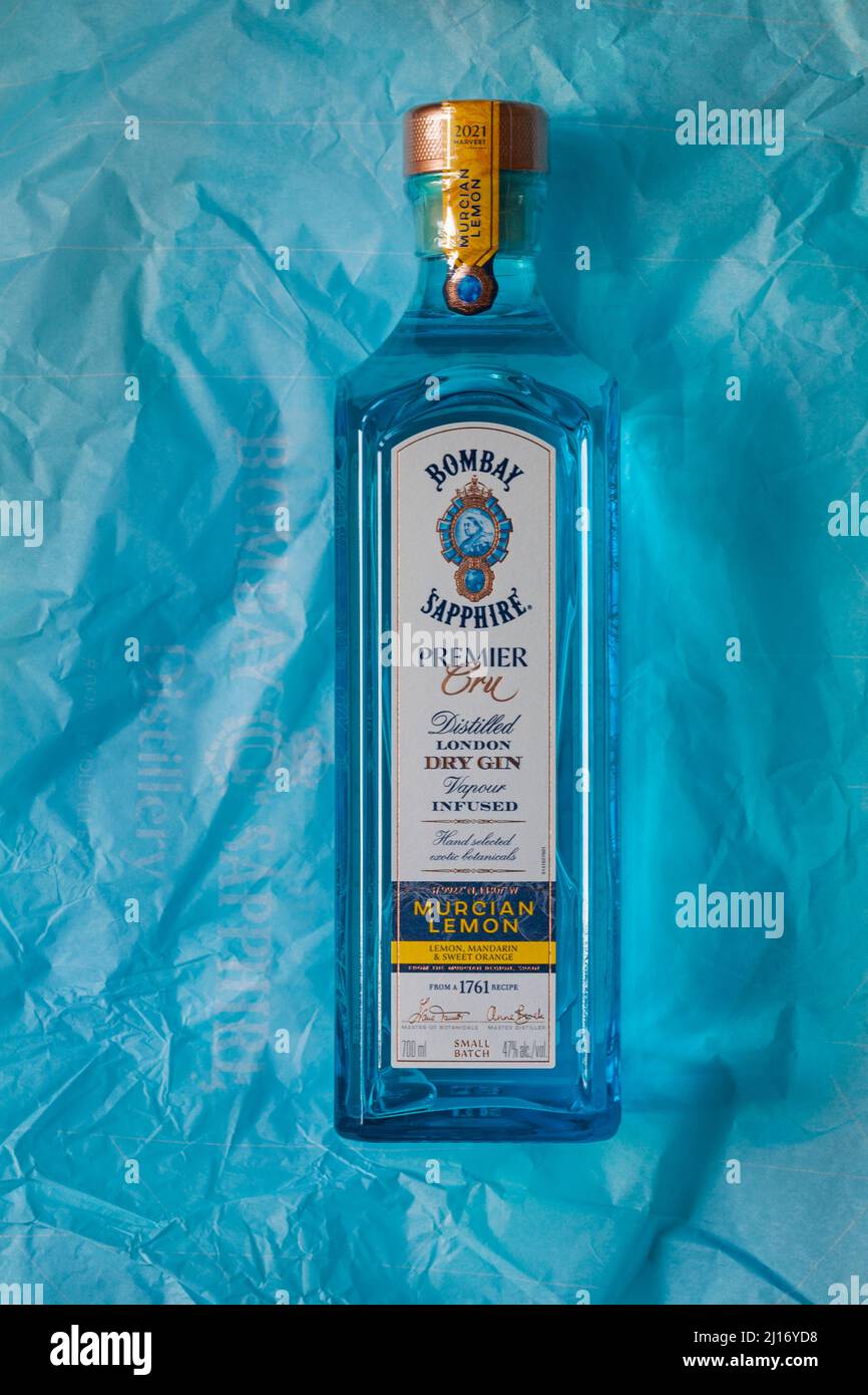 Bottiglia di Bombay Sapphire Premier Cru distillato London Dry Gin vapore infuso Murcian Lemon selezionato a mano esotici botanici su carta di tessuto blu Foto Stock