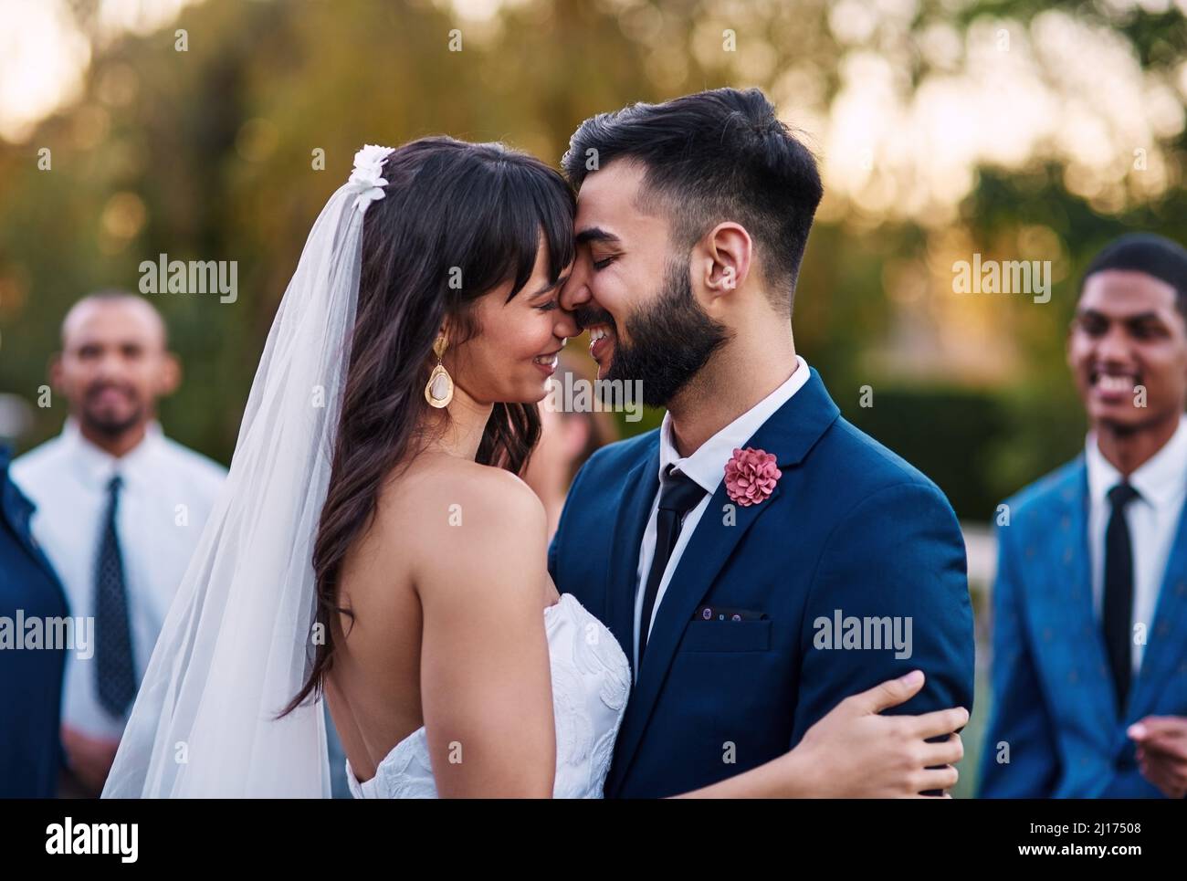 Ti amo sempre di più. Scatto corto di una coppia giovane e affettuosa sposata sorridente l'un l'altro il loro giorno di nozze con i loro ospiti dentro Foto Stock