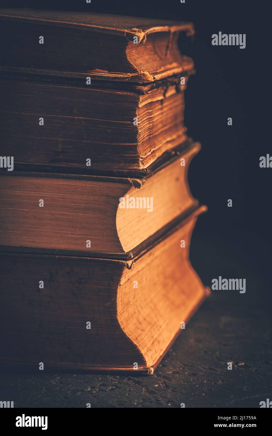 Pila di libri antichi rilegati in pelle su sfondo scuro Foto Stock