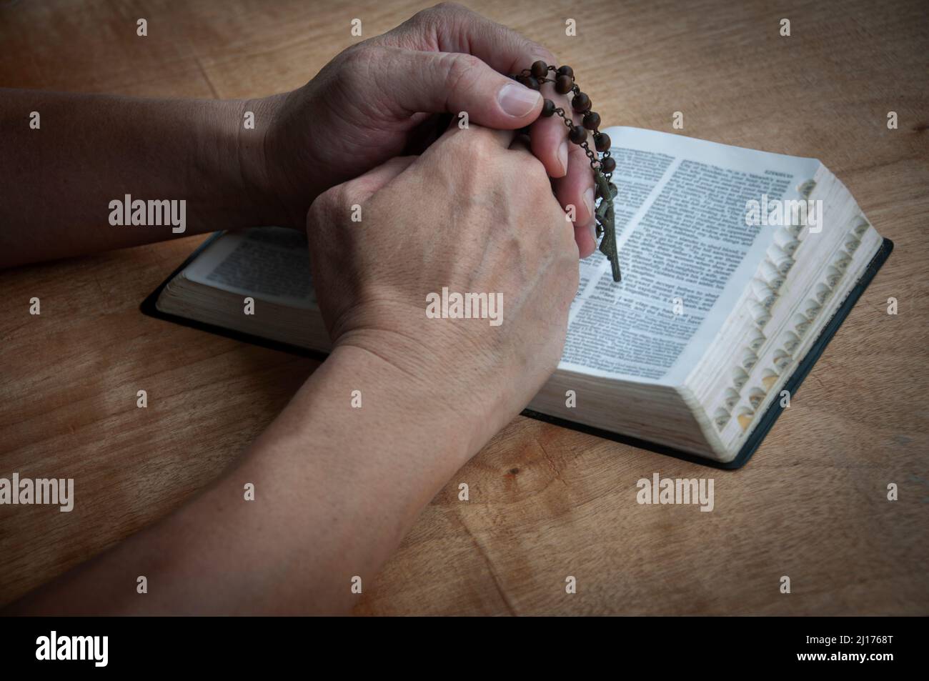 Mano che tiene Rosario su una Sacra Bibbia che prega. Cristianesimo e preghiera concetto. Foto Stock