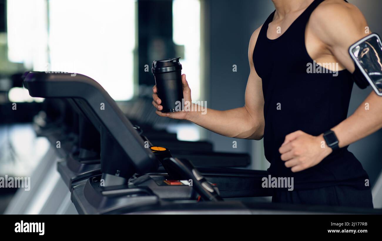 Stile di vita sportivo. Atleta maschile irriconoscibile che fa jogging sul tapis roulant presso la moderna palestra Foto Stock