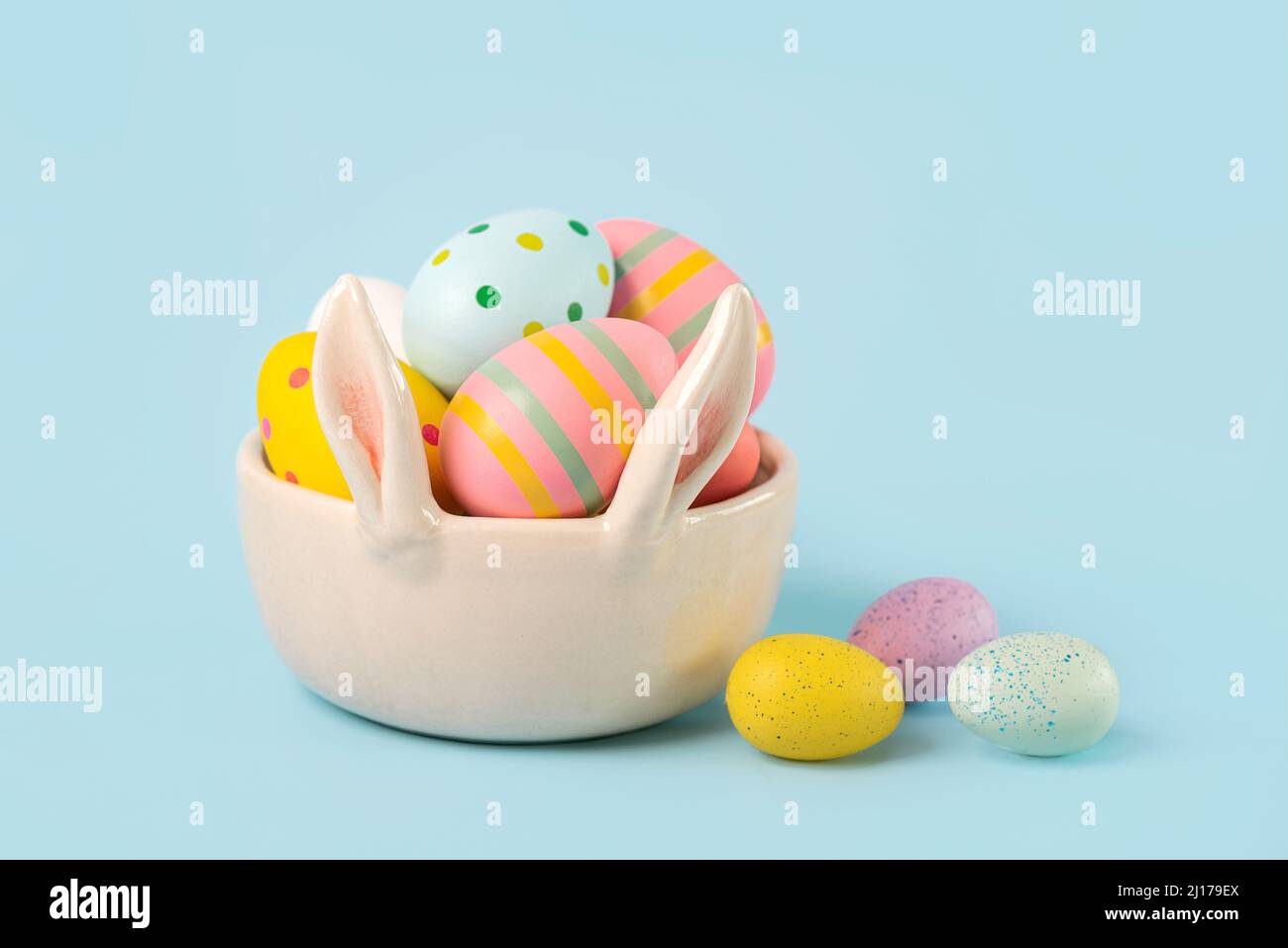 Buona Pasqua. Uova dipinte di pasqua colorate in una ciotola di orecchie conigliate su sfondo blu Foto Stock