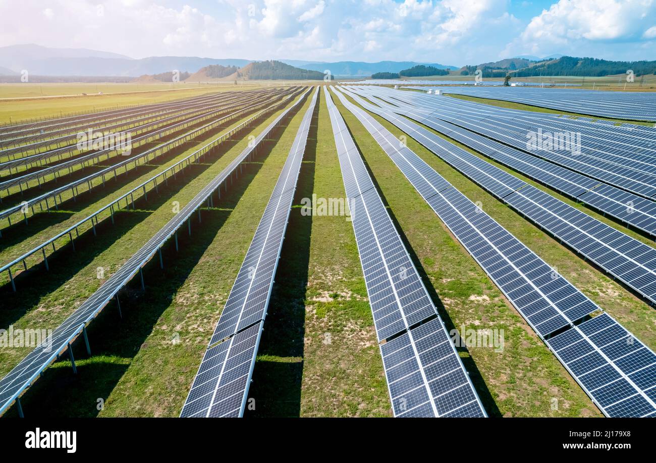 Pannello solare, fotovoltaico tra montagne e colline drone vista aerea. Azienda agricola che produce energia verde pulita. Foto Stock