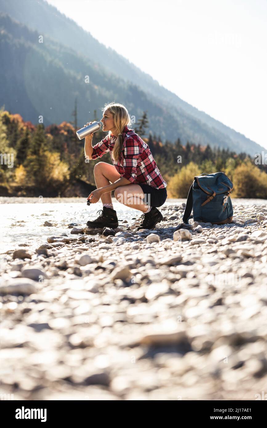 Austria, Alpi, donna su un viaggio escursionistico avente una interruzione in corrispondenza di un ruscello Foto Stock