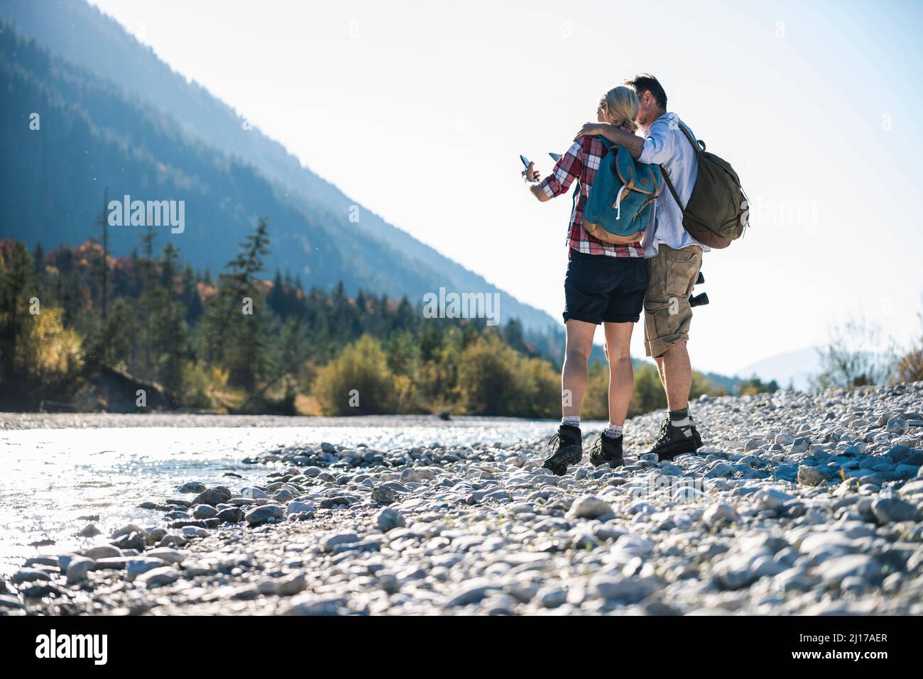 Austria, Alpi, giovane su un viaggio escursionistico guardando al telefono cellulare Foto Stock