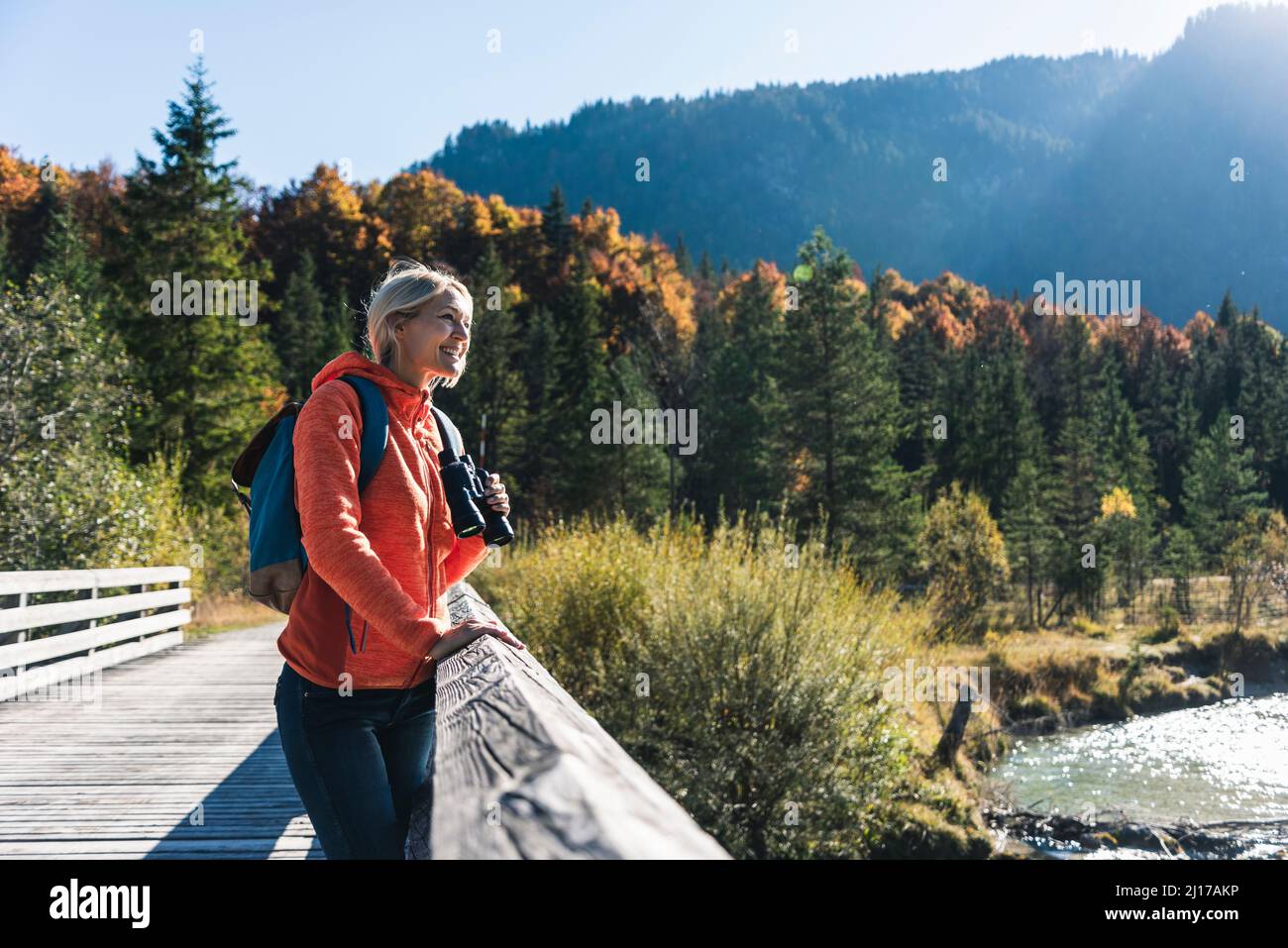 Austria, Alpi, donna su un viaggio escursionistico in piedi su un ponte con un binocolo Foto Stock