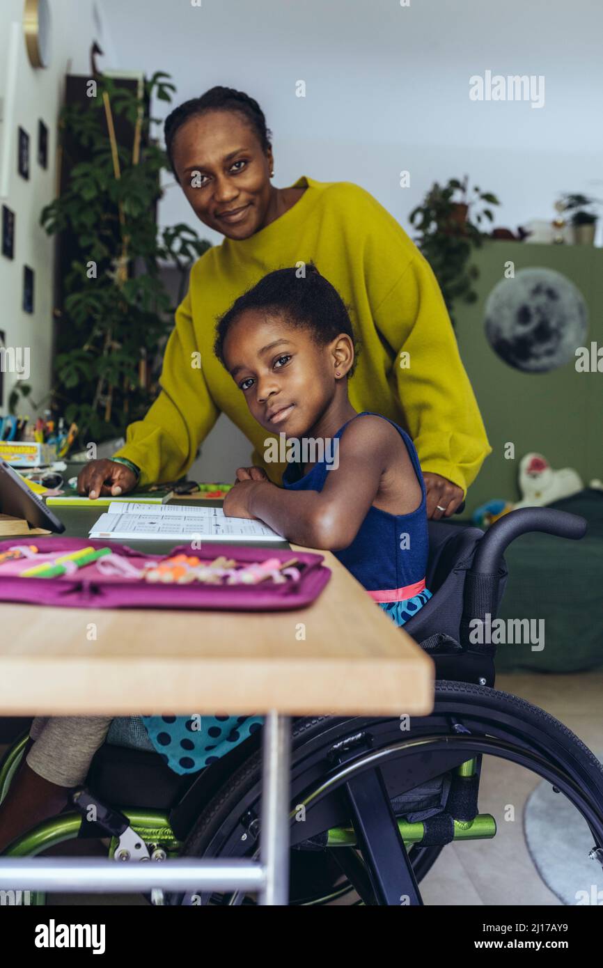 Ragazza disabile che studia da madre in camera da letto Foto Stock