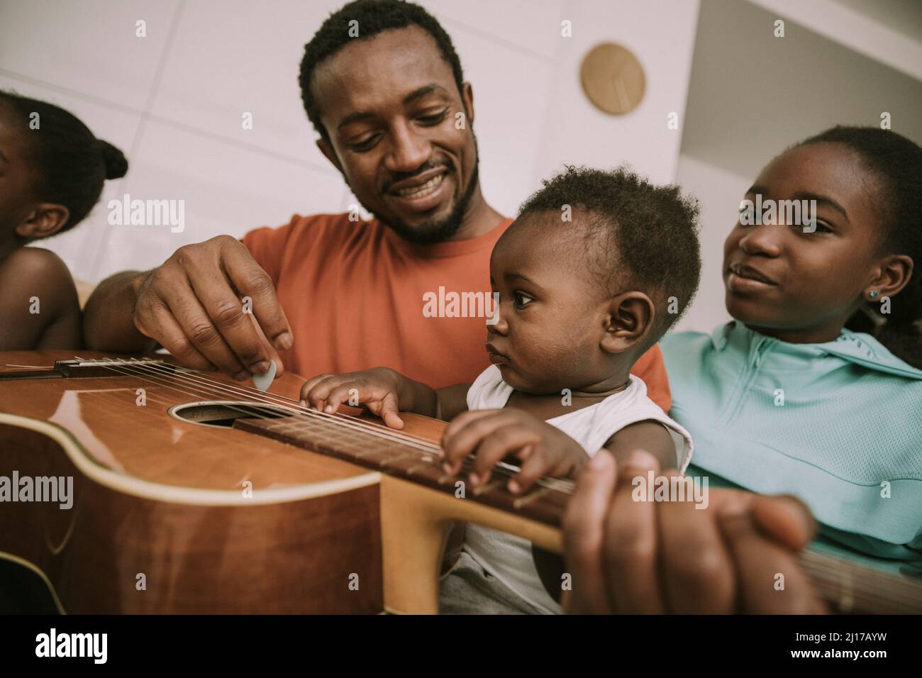 Padre che suona la chitarra da bambini a casa Foto Stock
