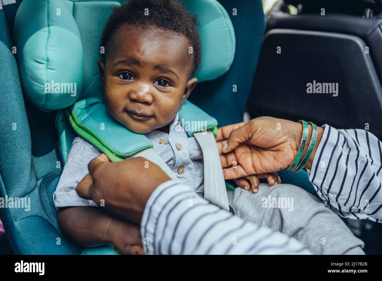 Madre che controlla le fibbie nella sede dell'automobile del bambino Foto Stock
