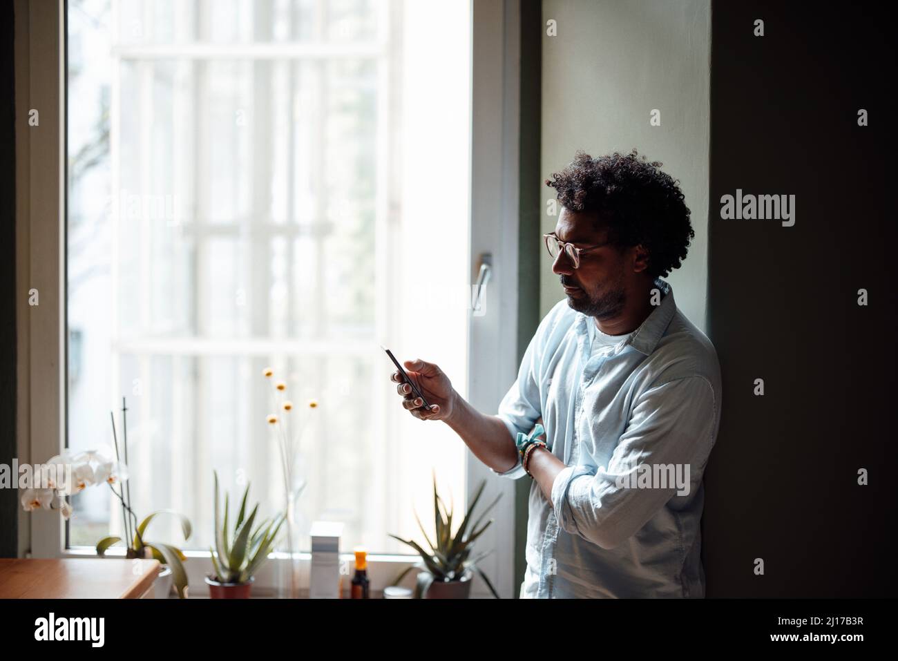 Messaggistica di testo uomo tramite telefono cellulare a casa Foto Stock