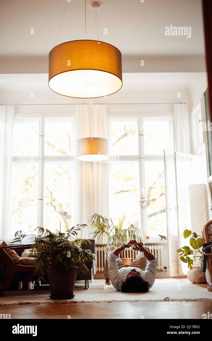 Uomo che utilizza il telefono cellulare sdraiato sul pavimento in soggiorno Foto Stock