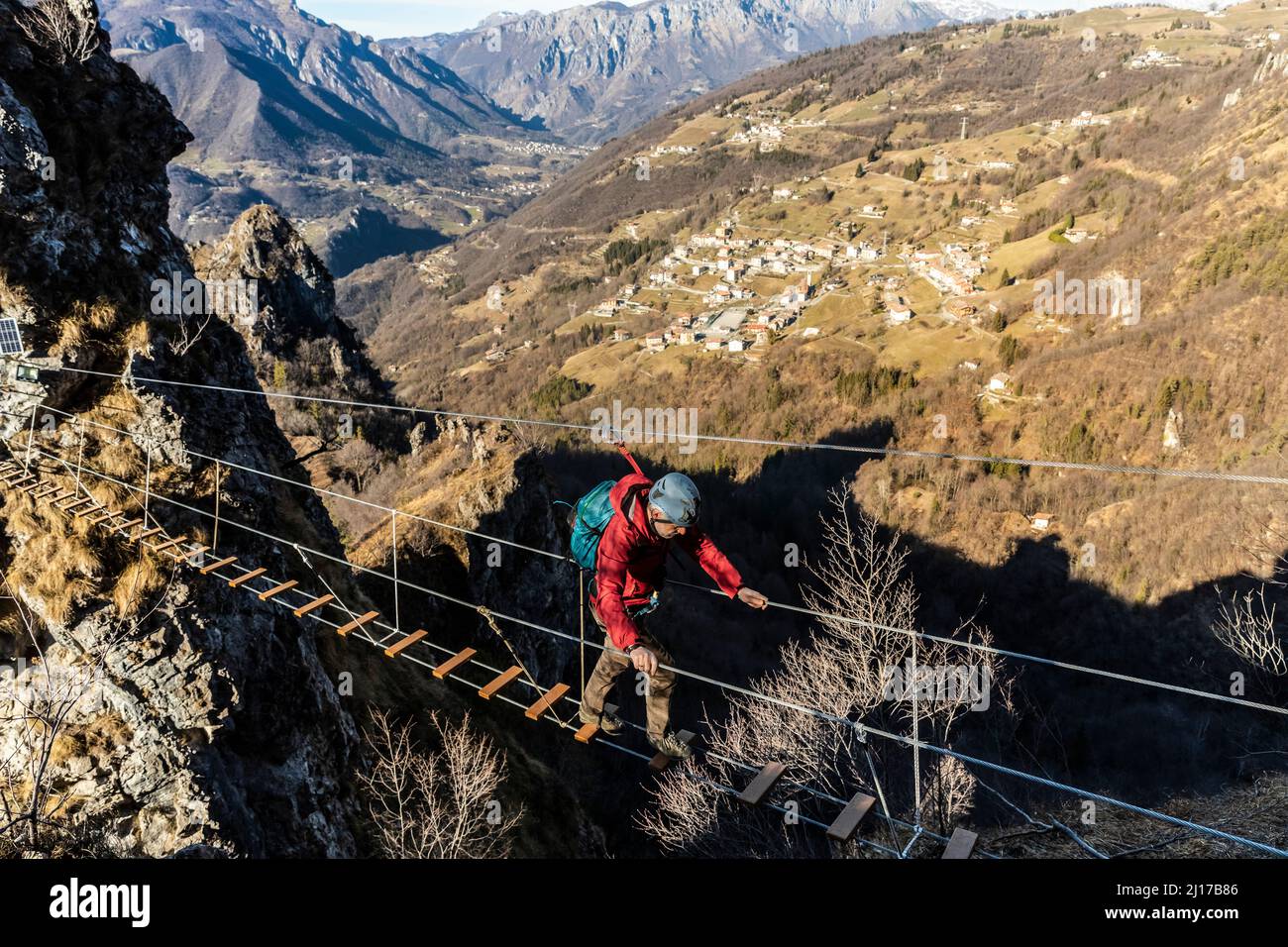 Uomo avventuroso che attraversa il ponte tibetano, alpi Orobie, Bergamo, Italia Foto Stock