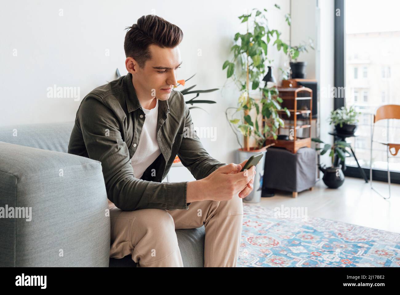 Messaggi di testo per i giovani tramite smartphone nel salotto di casa Foto Stock