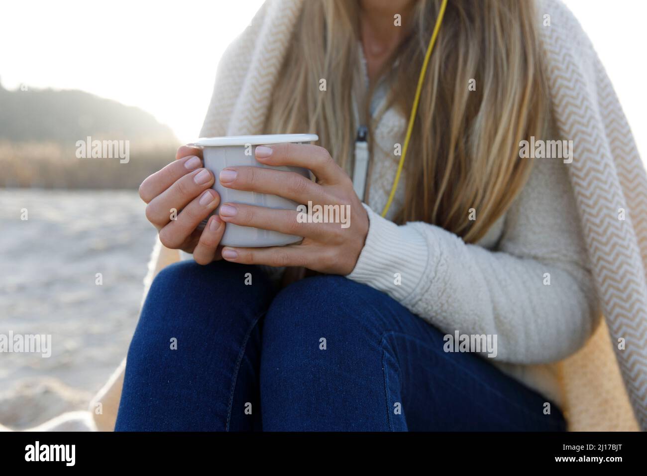 Donna bionda in abiti caldi che tiene una tazza di tè Foto Stock
