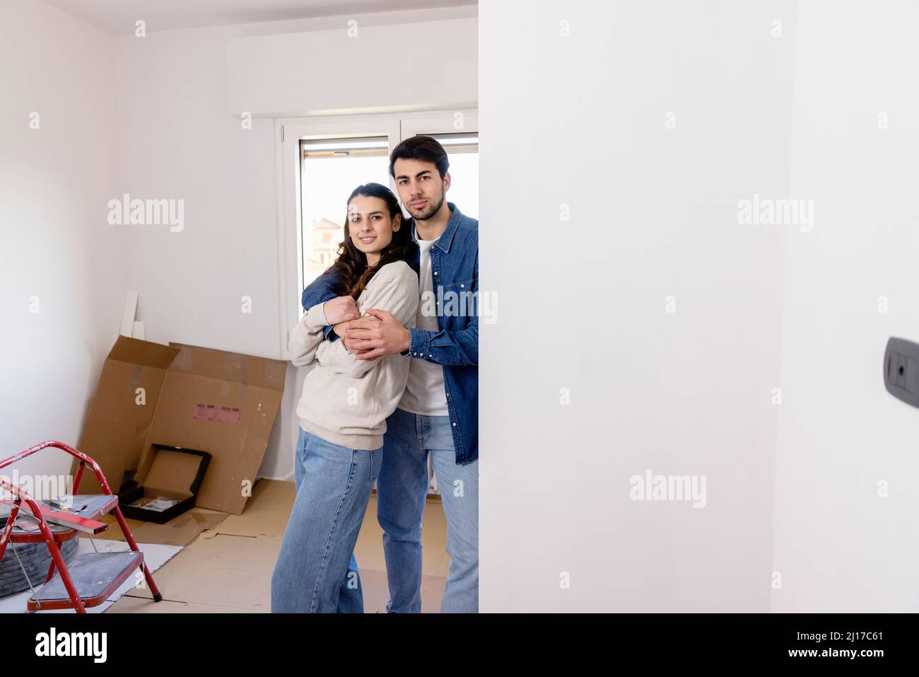 Coppia giovane che abbraccia a casa lavori di ristrutturazione Foto Stock
