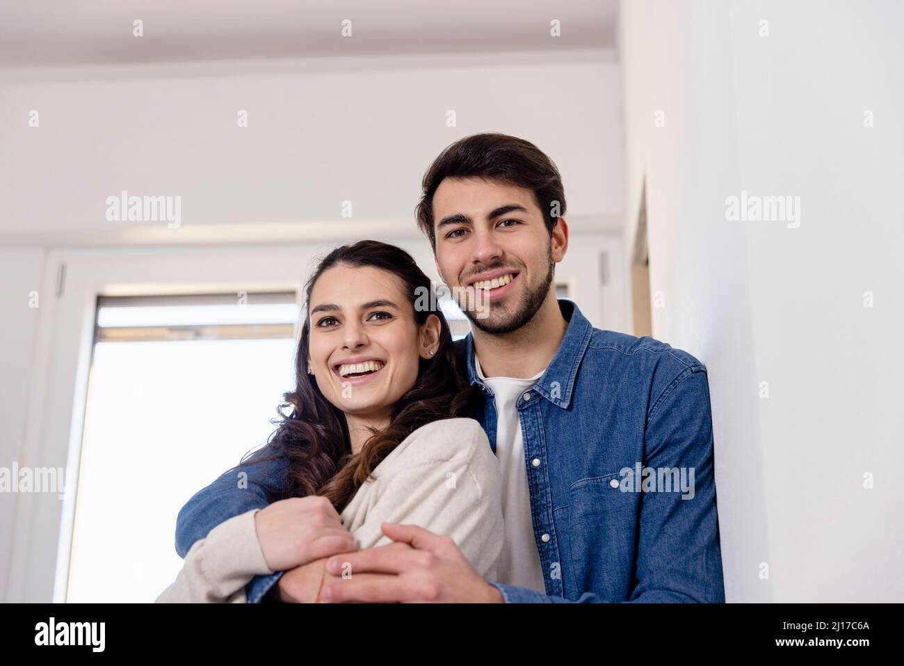 Coppia sorridente che si abbraccia a casa un lavoro di ristrutturazione Foto Stock
