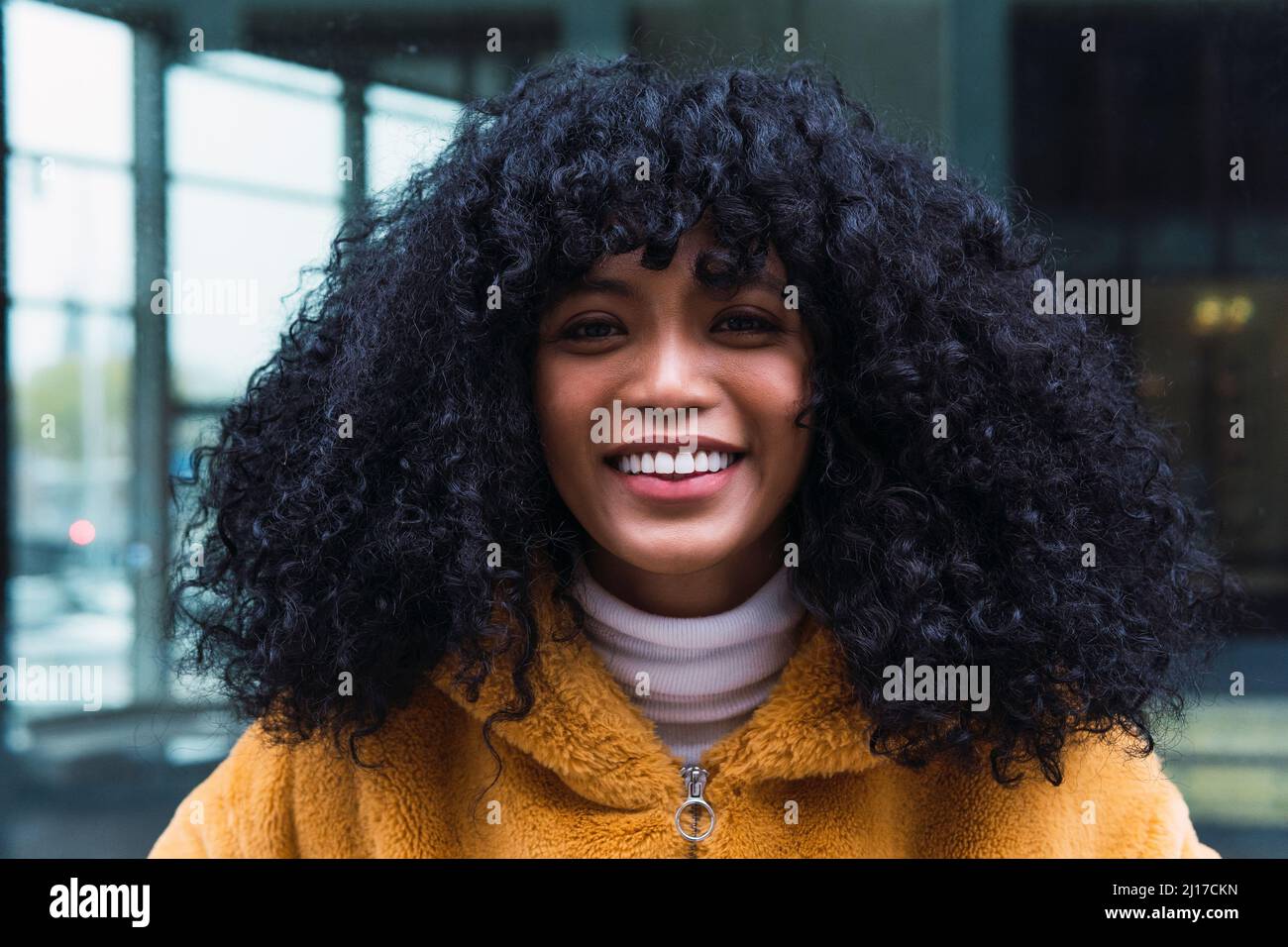 Donna sorridente con capelli ricci neri Foto Stock