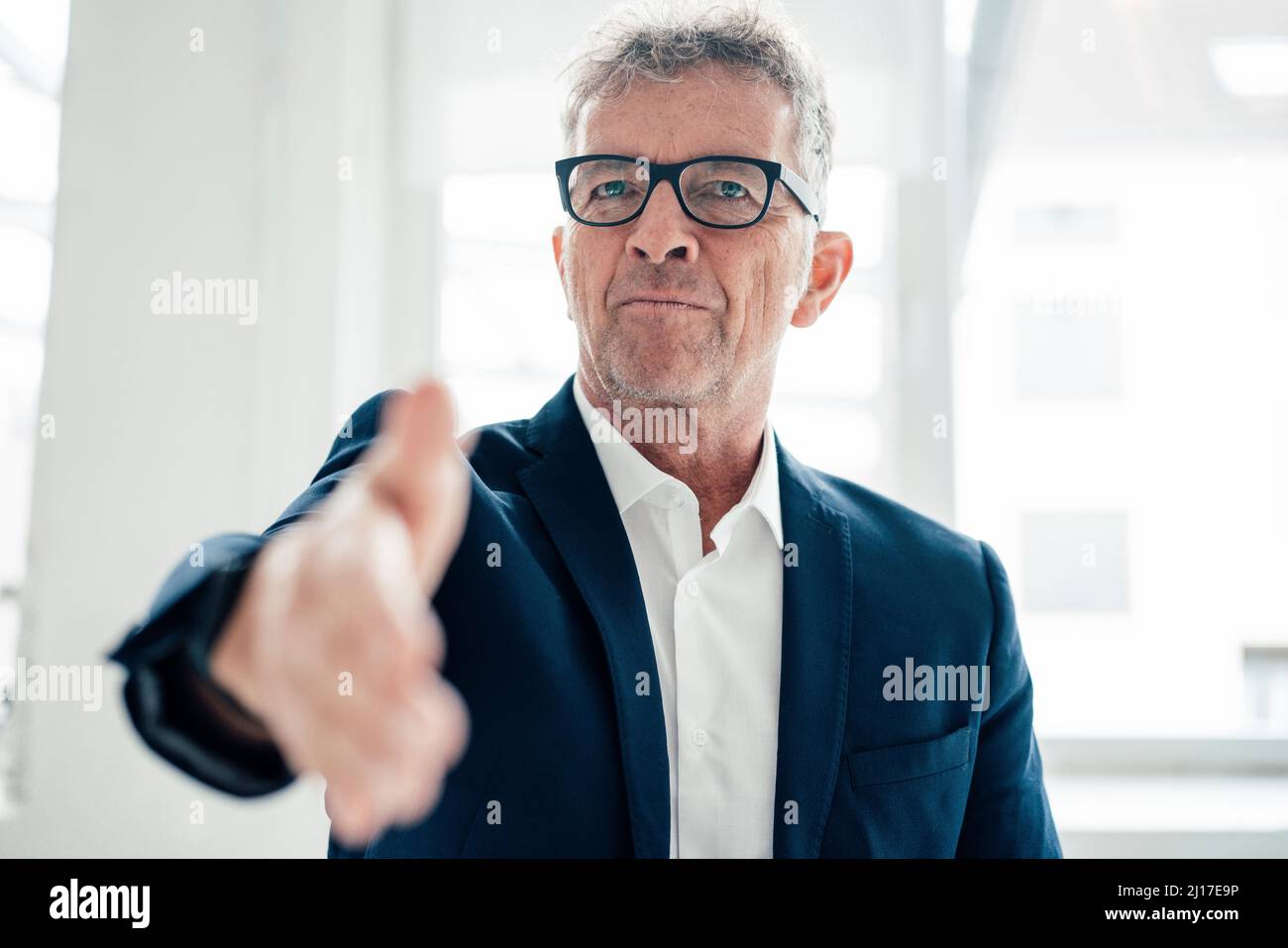 Uomo d'affari che offre handshake sul posto di lavoro Foto Stock