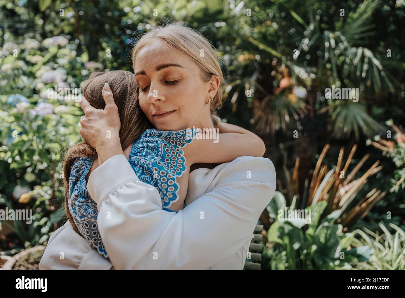 Madre che abbraccia la figlia nel cortile posteriore Foto Stock